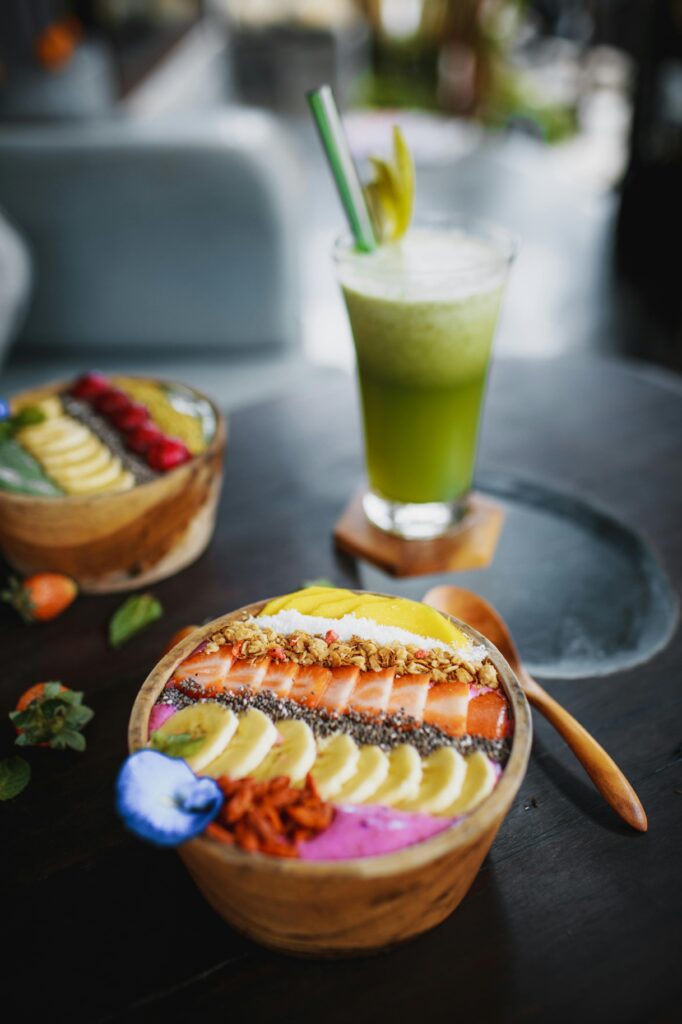 Vibrant acai bowl with fruits and a refreshing green juice on a wooden table.